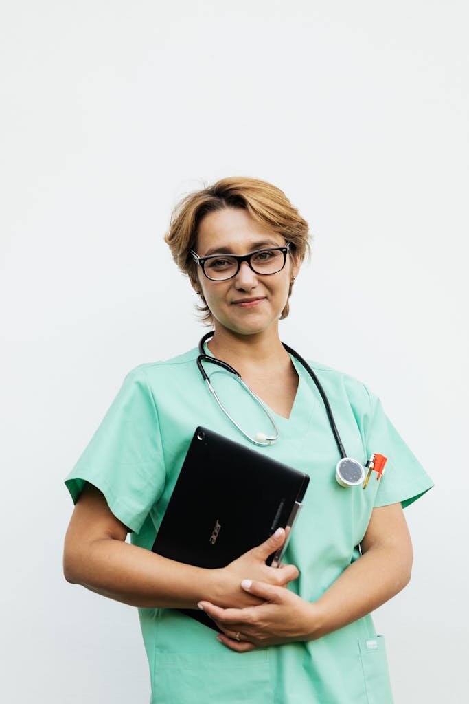 Confident female nurse with eyeglasses holding a tablet and stethoscope. Ideal for healthcare-related content.